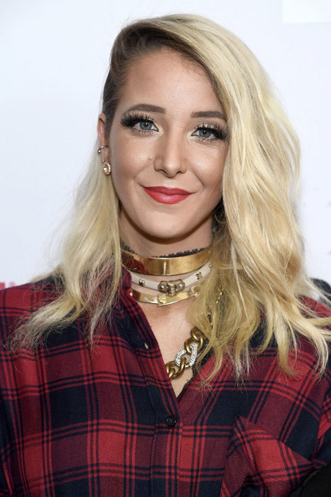 Jenna Marbles is smiling and wear red shirt and the chains in her neck are looking beautiful.