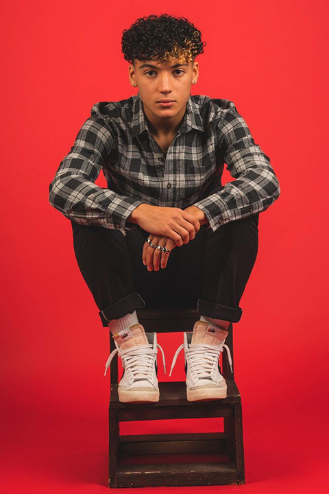 Maximo Rivano is sitting on a bench and posing for a picture.